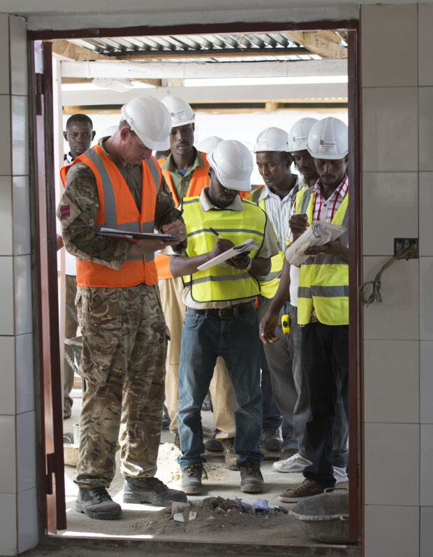 Staff Sergeant Johnson from 62 Works Group Royal Engineers checking over the buildings of the Ebola Treatment Centre with the Sierra Leone contractors.