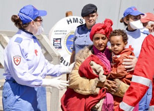 Royal Navy personnel and Italian staff assist migrants disembarking from HMS Bulwark in Taranto, Italy on 30th May 2015 following their rescue in the Mediterranean on 28th May.
