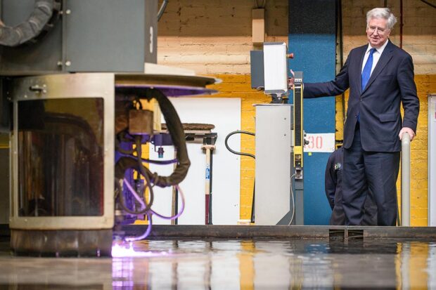 Secretary of State for Defence Michael Fallon operates the laser cutting machine.