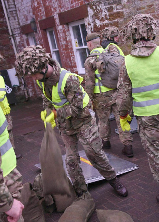 The Army has been called in to support efforts to protect flood-hit areas of Cumbria amid fears that more heavy rain will fall on Christmas Day. People are set to spend the day putting out sandbags in preparation and flood defence gates have been closed in Cockermouth, Carlisle and Keswick. Cumbria has suffered severe flooding three times this month. The Ministry of Defence said one company from 2nd Battalion Duke of Lancaster's Regiment (2LANCS), based at Weeton Barracks near Preston, are being deployed to affected areas on Christmas Day morning. Rain will spread across Wales and northern England through the course of Christmas Day, reaching southern parts of Scotland during the early hours of Boxing Day, with prolonged spells forecast for south Cumbria. The county has already recorded the wettest December since records began in 1910. Defence Secretary Michael Fallon said: "Even at Christmas our Armed Forces are keeping us safe. Once again they are responding to the Cumbria floods with a level of commitment that is to be applauded." Pic - Soldiers from 2LANCS help set up flood defences in Appleby.