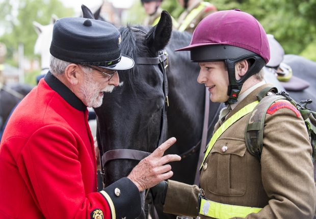 Ex Household Cavalry Soldier Michael Paling passes his knowledge onto Trooper Smith. Sixty soldiers and horses of the Household Cavalry joined Chelsea Pensioners for breakfast after the Regiment’s busiest week of the year. The scarlet coats of the Pensioners met with the shining black coats of over 60 cavalry steeds at Royal Hospital Chelsea this morning, as the veterans offered bacon sandwiches, tea, coffee and Bucks Fizz to the soldiers of the Queen’s mounted bodyguard. After a two week period containing three 2am rehearsals, four royal escorts, eight musical ride performances in Windsor, one midnight horse move and the State Opening of Parliament, the men and horses of the Household Cavalry Mounted Regiment have rarely been so exhausted. Major Alex Owen (30), the Blues and Royals Squadron Leader said: “In the month of Her Majesty’s 90th Birthday celebrations and the State Opening of Parliament what better way for us to celebrate a job well done than with the men and women who have dedicated their entire lives in the service of the Crown. Photographer: Sergeant Rupert Frere RLC (Phot)