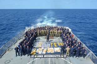 The Ship's Company of HMS Monmouth with the drugs recovered from a fishing dhow intercepted in the Indian Ocean. 
