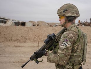 An Army soldier patrols a location in Iraq carrying a rifle.