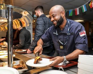 A Royal Navy sailor putting food on his plate