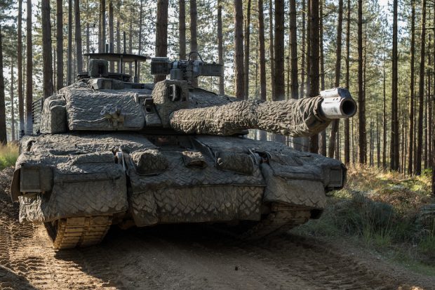 A British Army tank adorned with camoflague in a forest