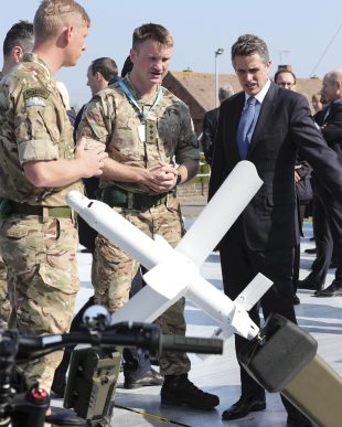The Defence Secretary is shown examples of the British Military Industry's work by some soldiers.