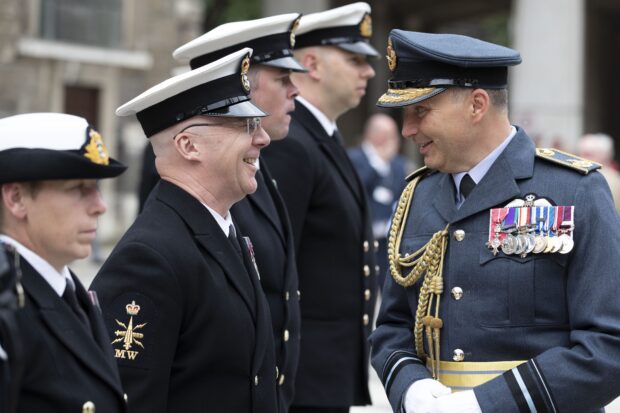 Air Vice-Marshal Ian Gale greets members of the Armed Forces who are lined up in uniform.