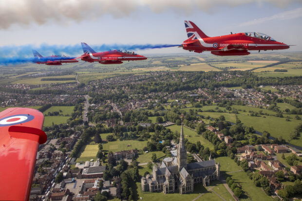 The view from the cockpit of a Red Arrows aircraft, showing the Red Arrows in formation over Salisbury Cathedral